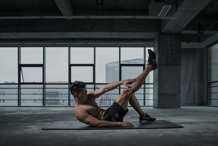 Man doing bicycle crunches in a gym setting, emphasizing cardio training.