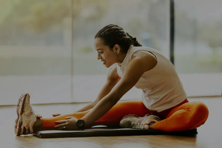 Man sitting on the floor and stretching his legs forward in a modern room.